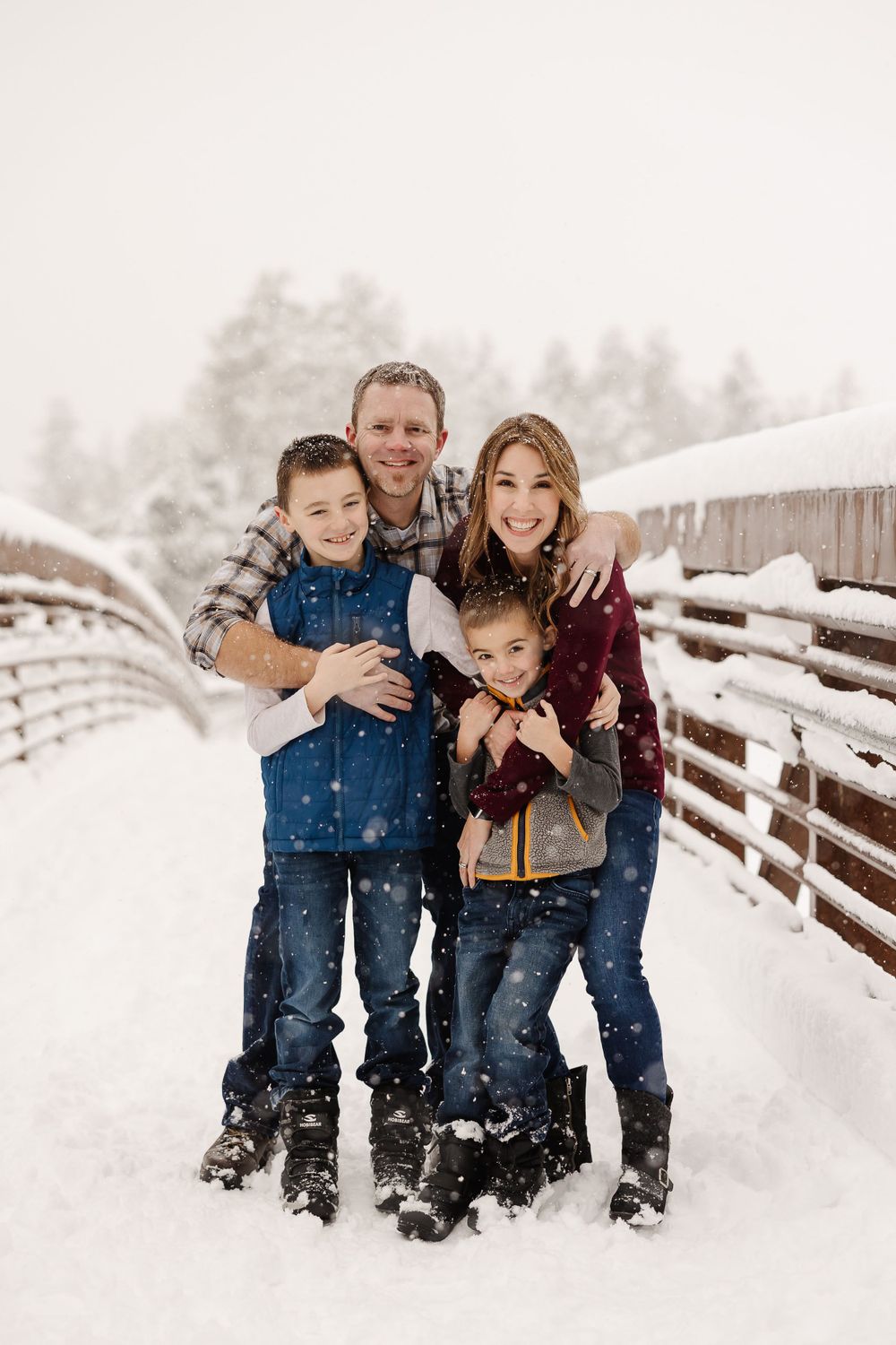 Winter family portrait with everyone bundled up in warm clothes standing in the snow.
