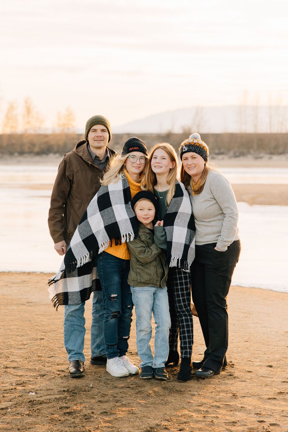 Group portrait at sunset on a beach with people bundled in winter clothing.