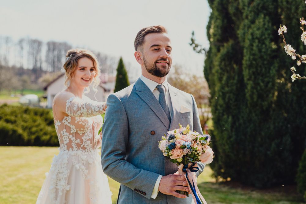 Couple sharing romantic moment in garden setting with spring flowers and greenery.