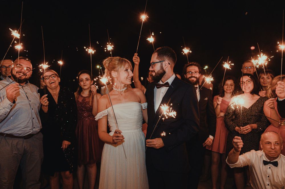 Wedding guests hold sparklers creating a magical nighttime atmosphere.
