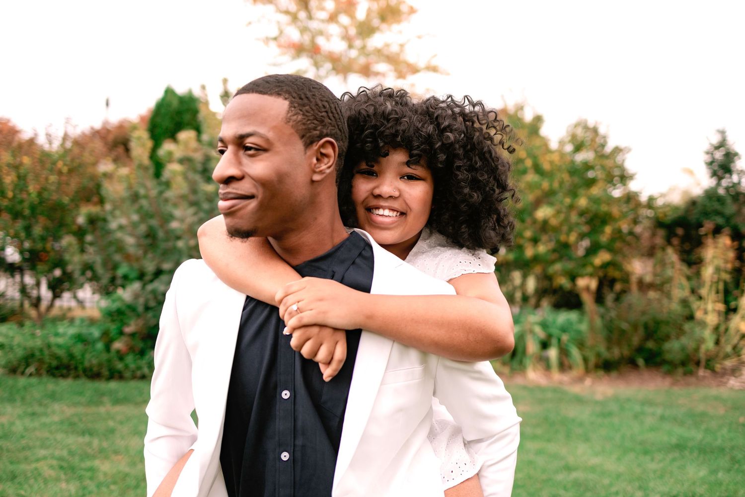 Happy Black couple sharing a piggyback ride in a green park during fall season.