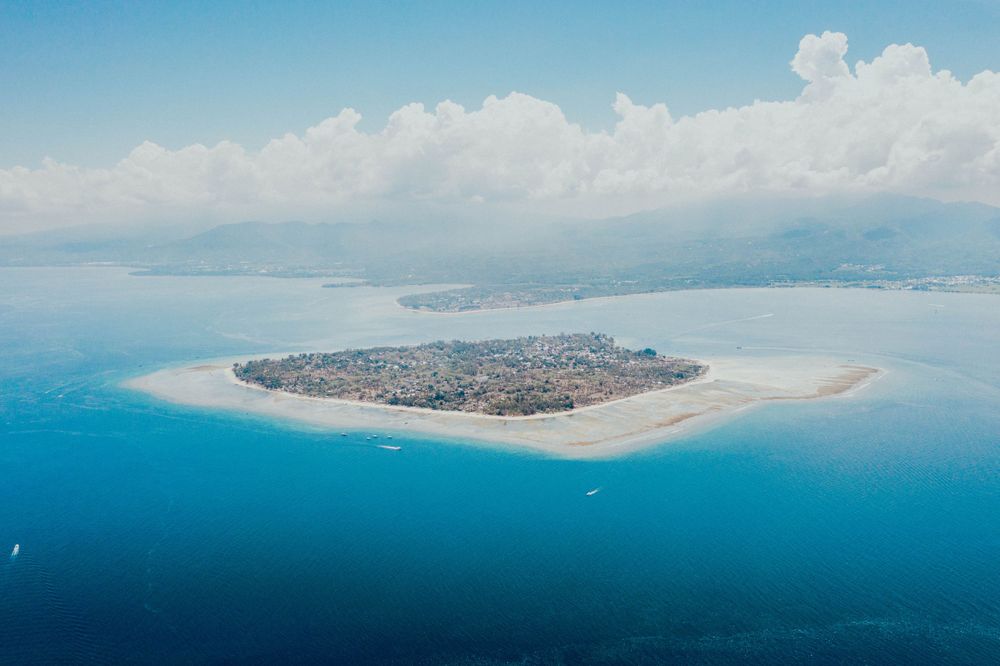 Aerial view of a tropical island surrounded by crystal clear turquoise waters and white sandy beaches.
