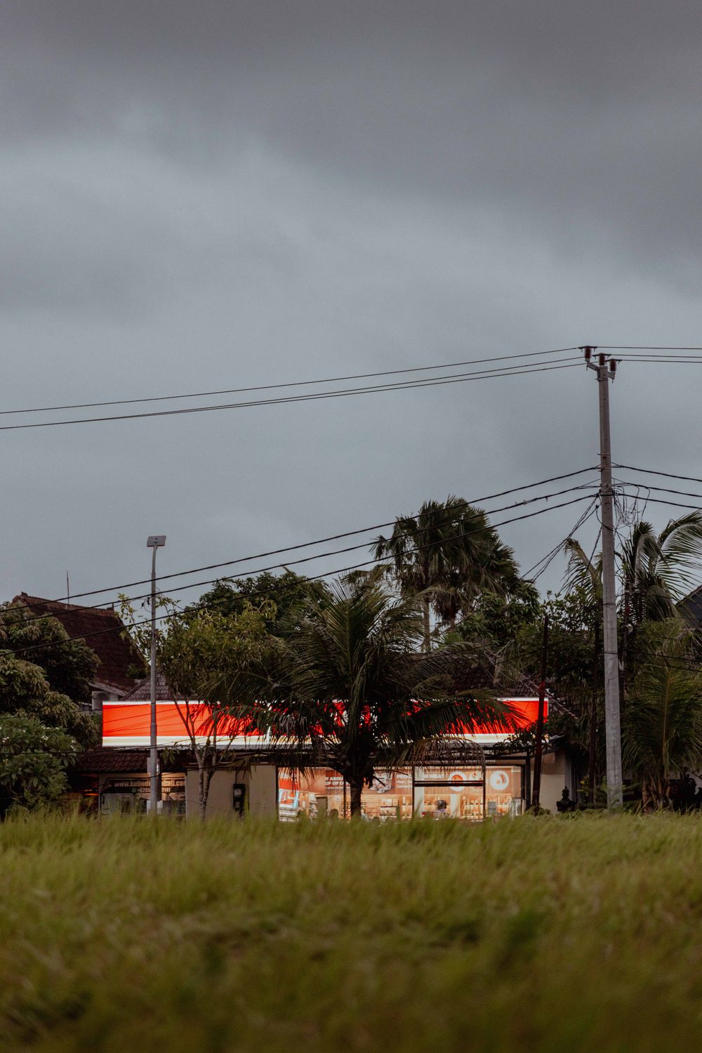 Moody landscape with orange building and power lines against cloudy grey sky.