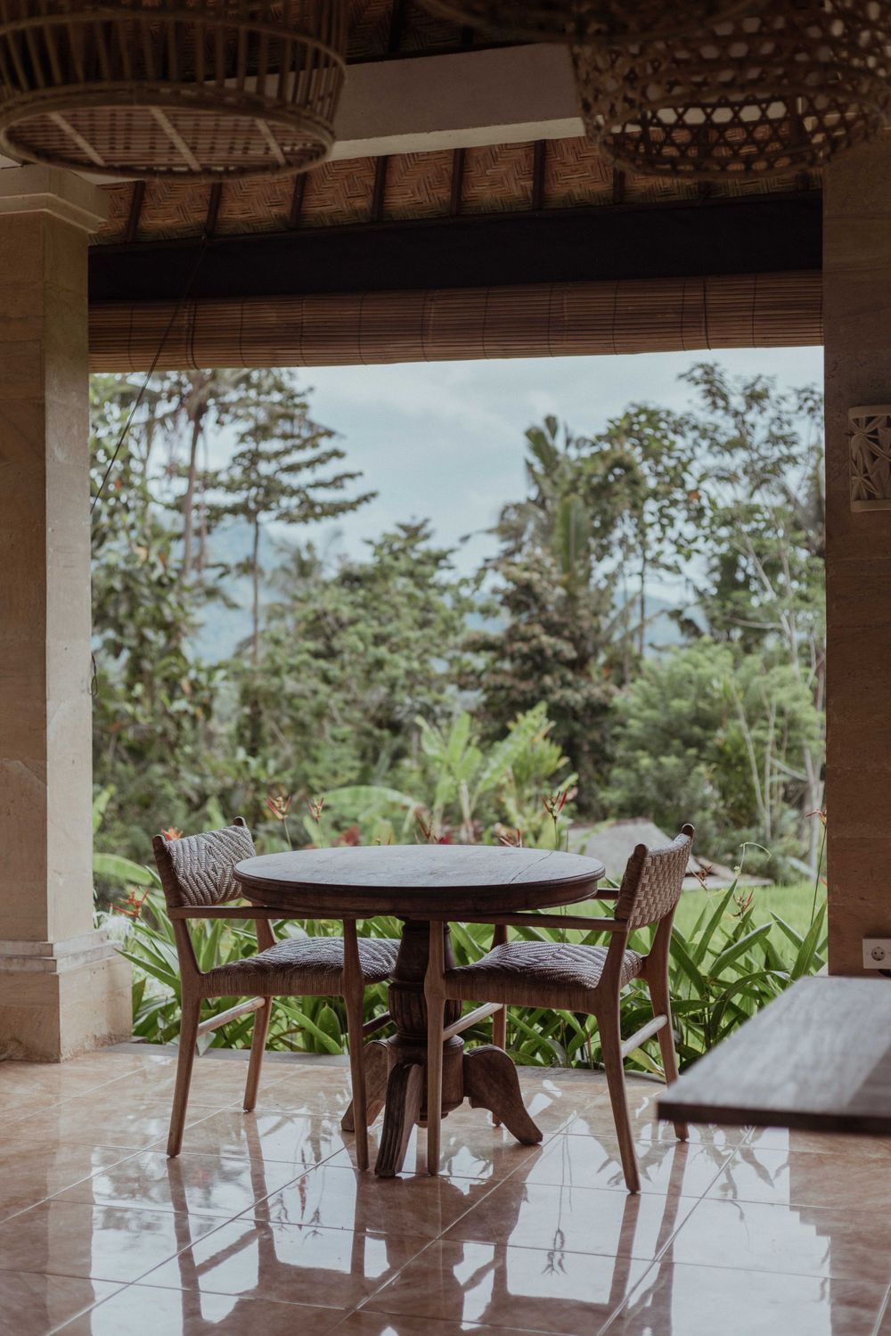 Outdoor dining table and chairs on a patio overlooking a lush tropical garden.