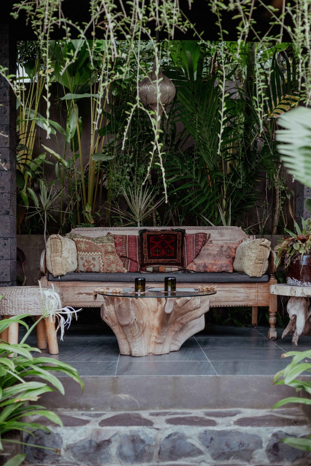 Cozy outdoor seating area with rustic wood furniture and hanging plants.