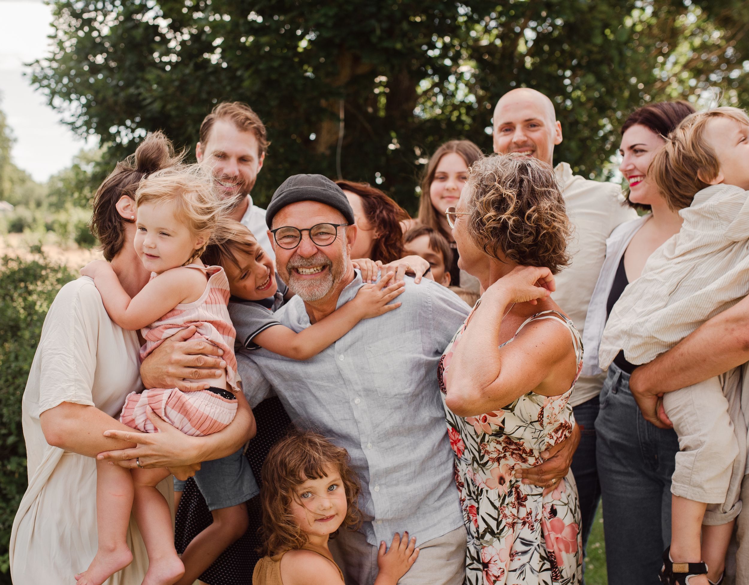 Candid moment of family joy and laughter during an outdoor gathering in white and beige attire.