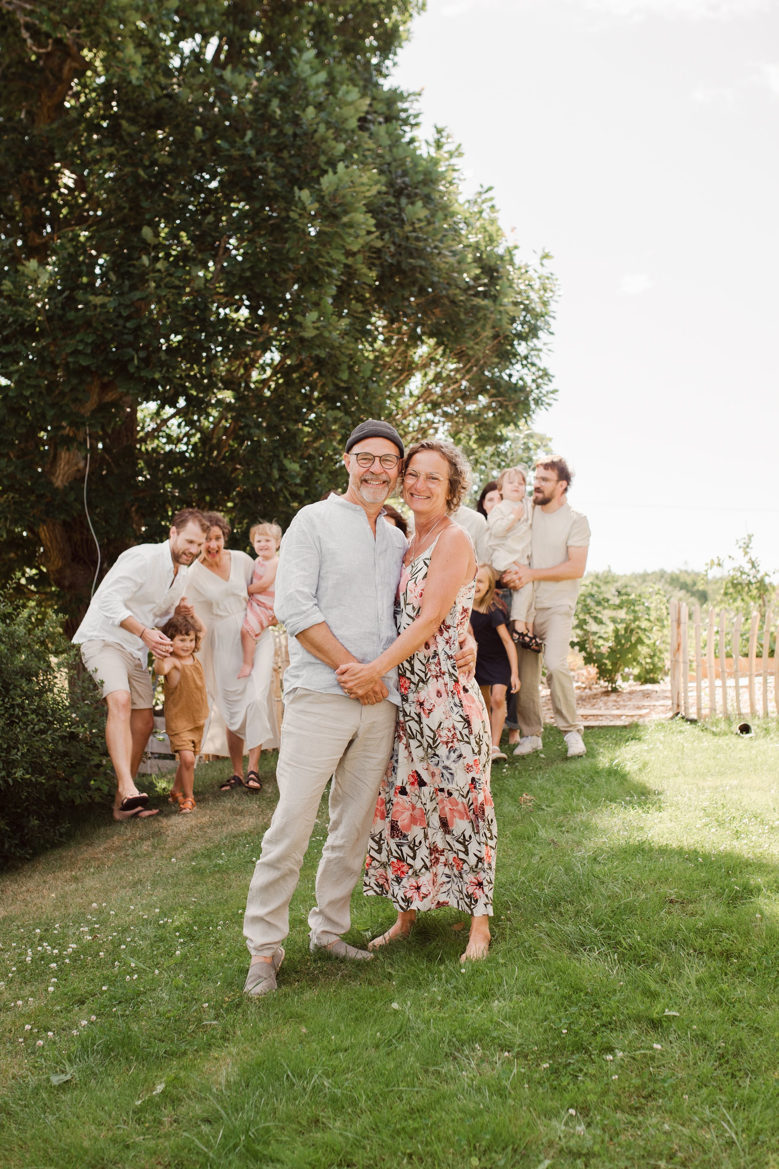 A couple poses together outdoors while others look on in the background.