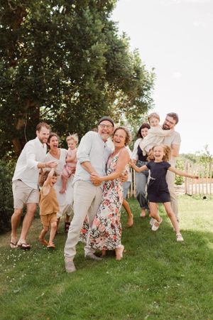 A large family group shares candid laughter during an outdoor photo session.