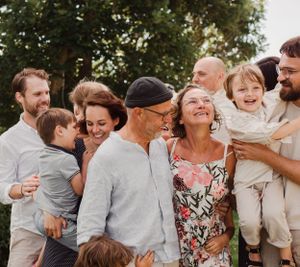 Family members share genuine laughter during an outdoor photo session in casual attire.