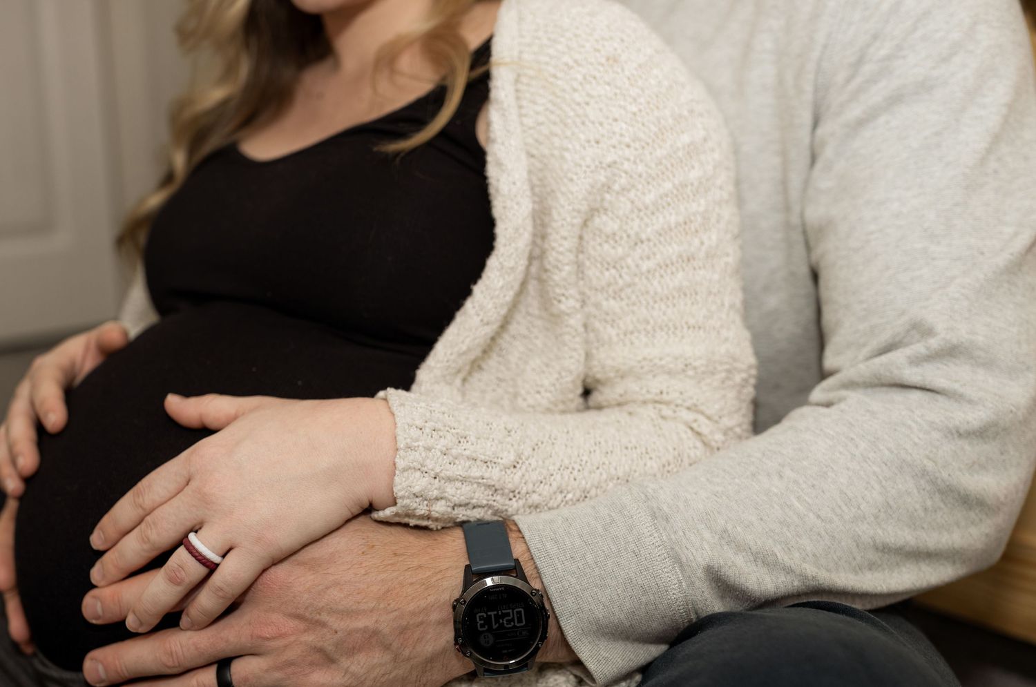 Couple in casual attire sits together with their black dog in a cozy home setting.