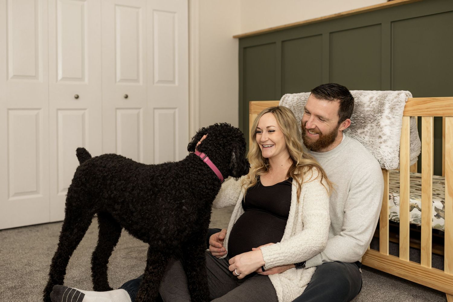 Sweet interaction between couple and their black dog in living room setting.