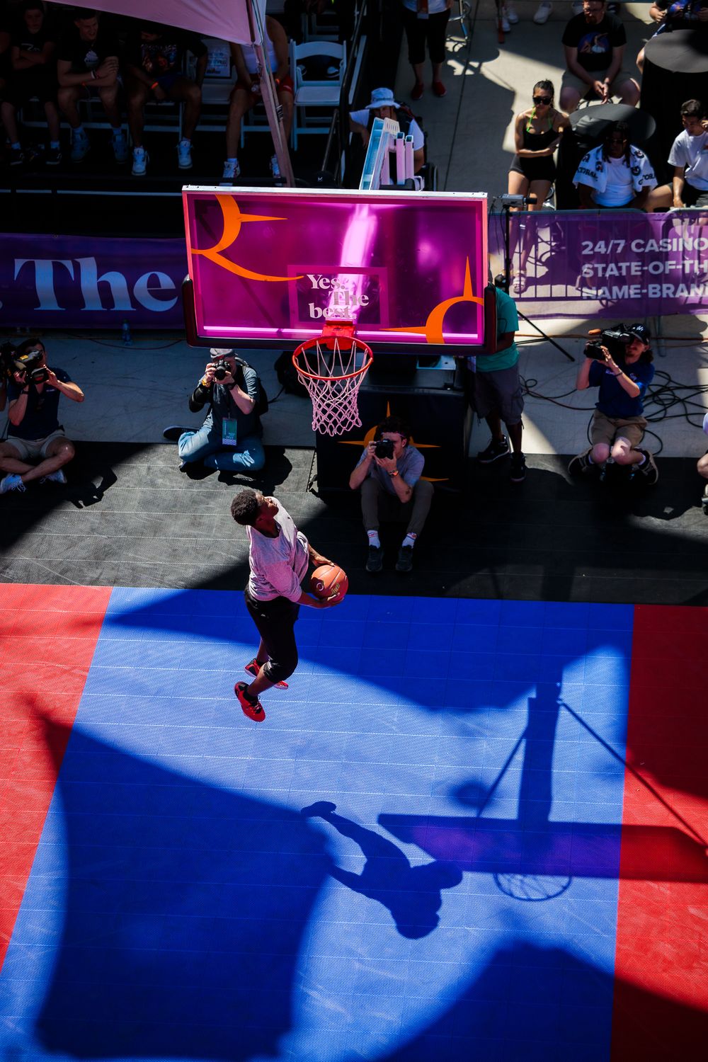 A man in a blue shirt and red shorts performs a dunk during the Hoopfest Dunk Contest.