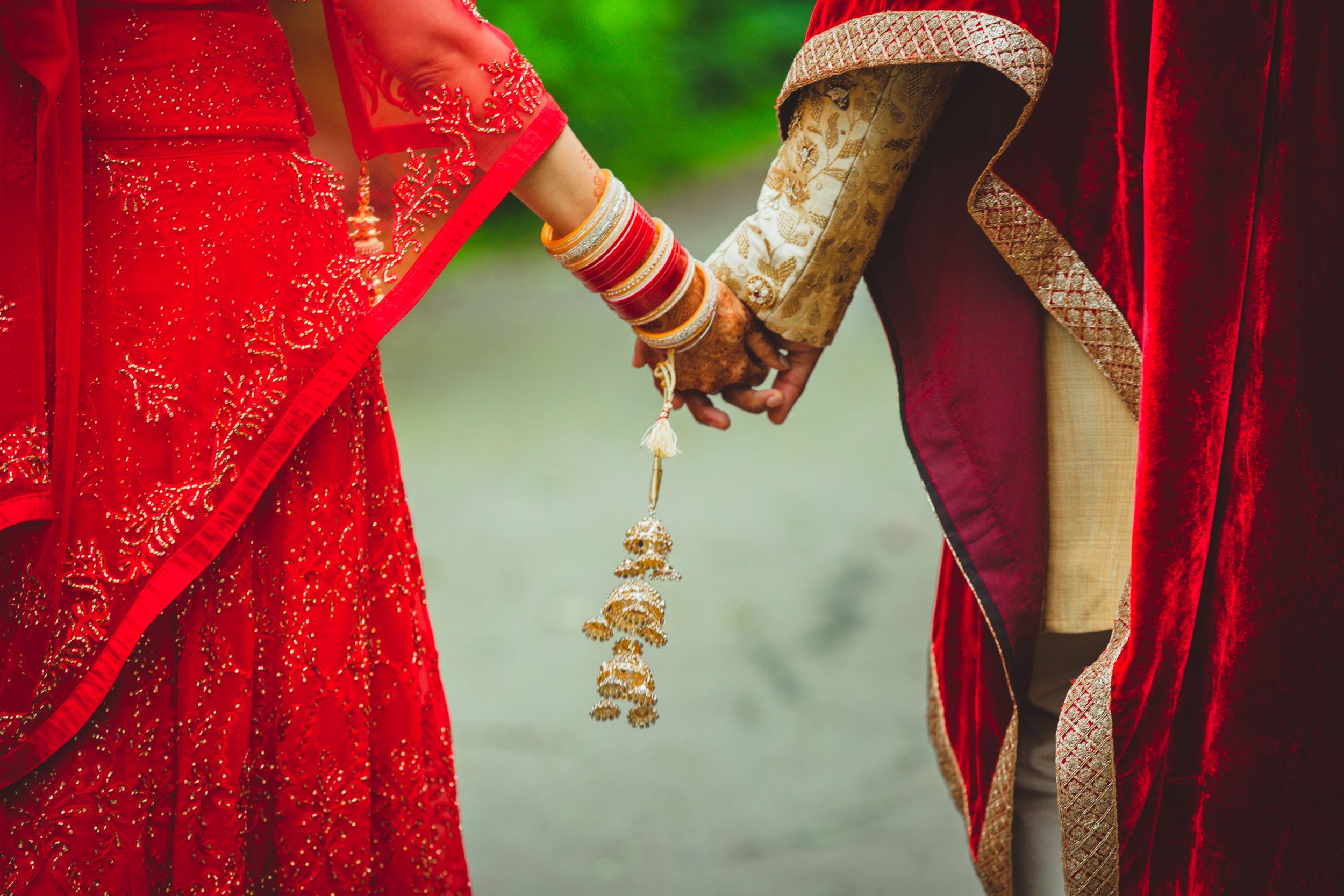 Close-up of decorated hands holding traditional Indian wedding kalire bangles.