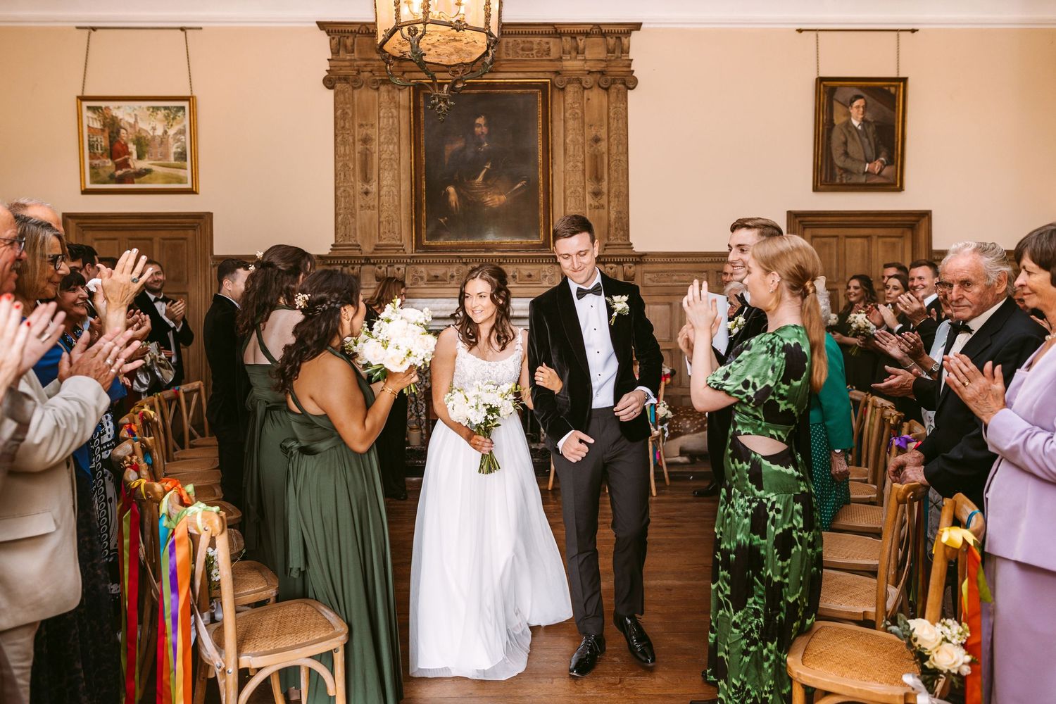 Wedding celebration in historic venue with guests clapping along wood-paneled walls.
