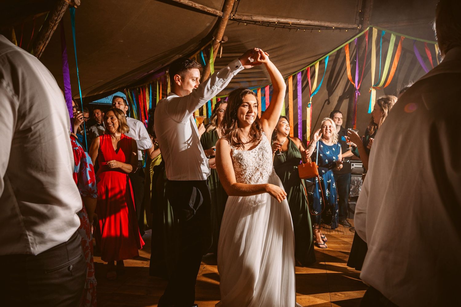 Lively wedding reception celebration with dancing under colorful streamers and lights.