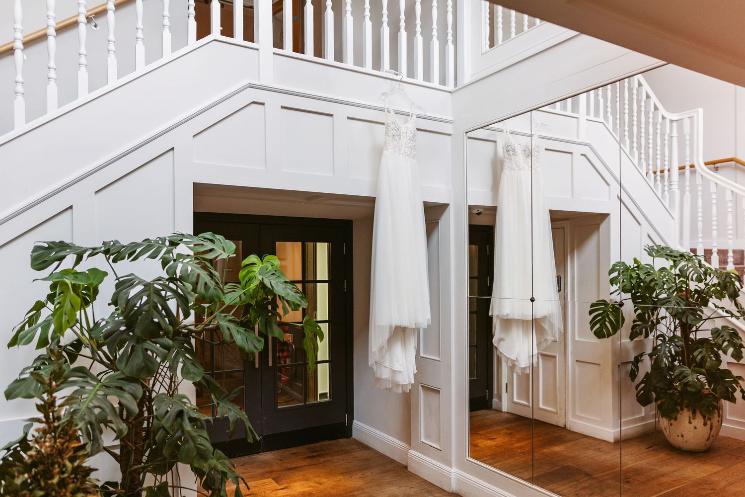 Modern white staircase interior with plants and natural lighting in an elegant home.