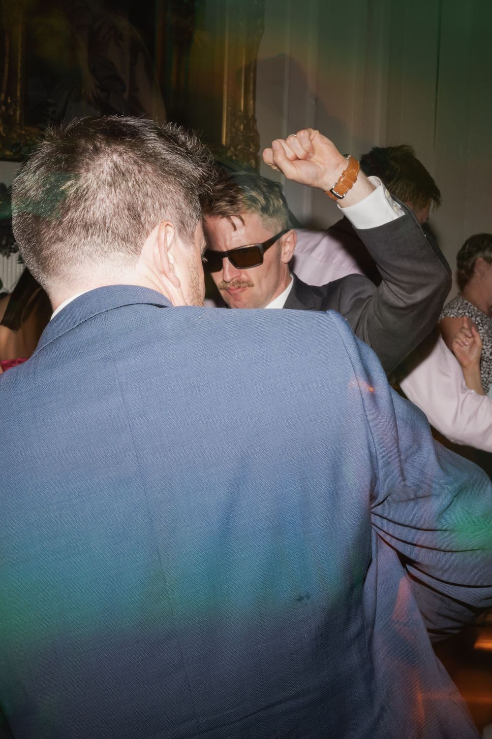 Guests dancing energetically at a dimly lit indoor party with atmospheric green lighting.
