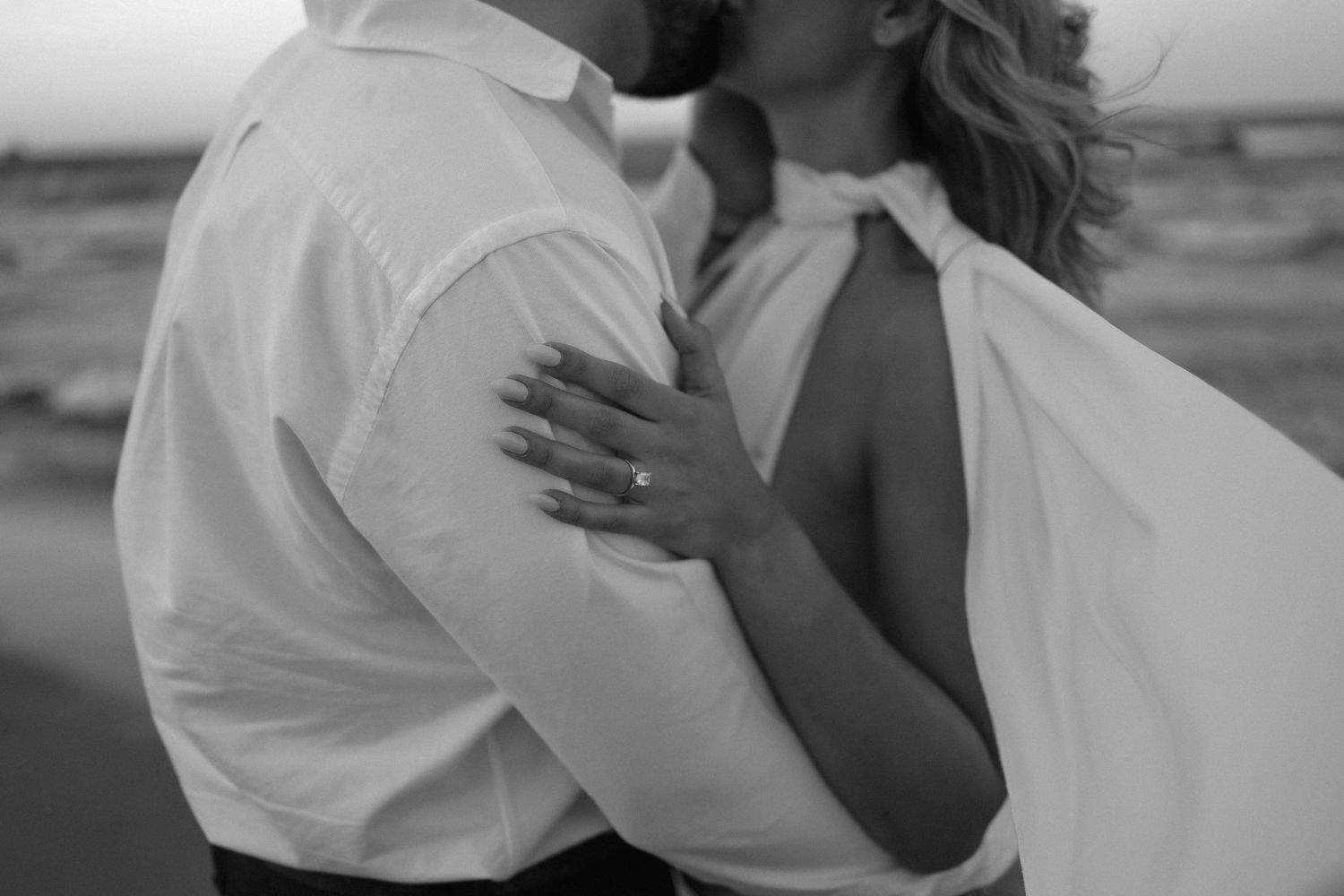 Intimate black and white photo of a couple sharing a romantic moment outdoors.