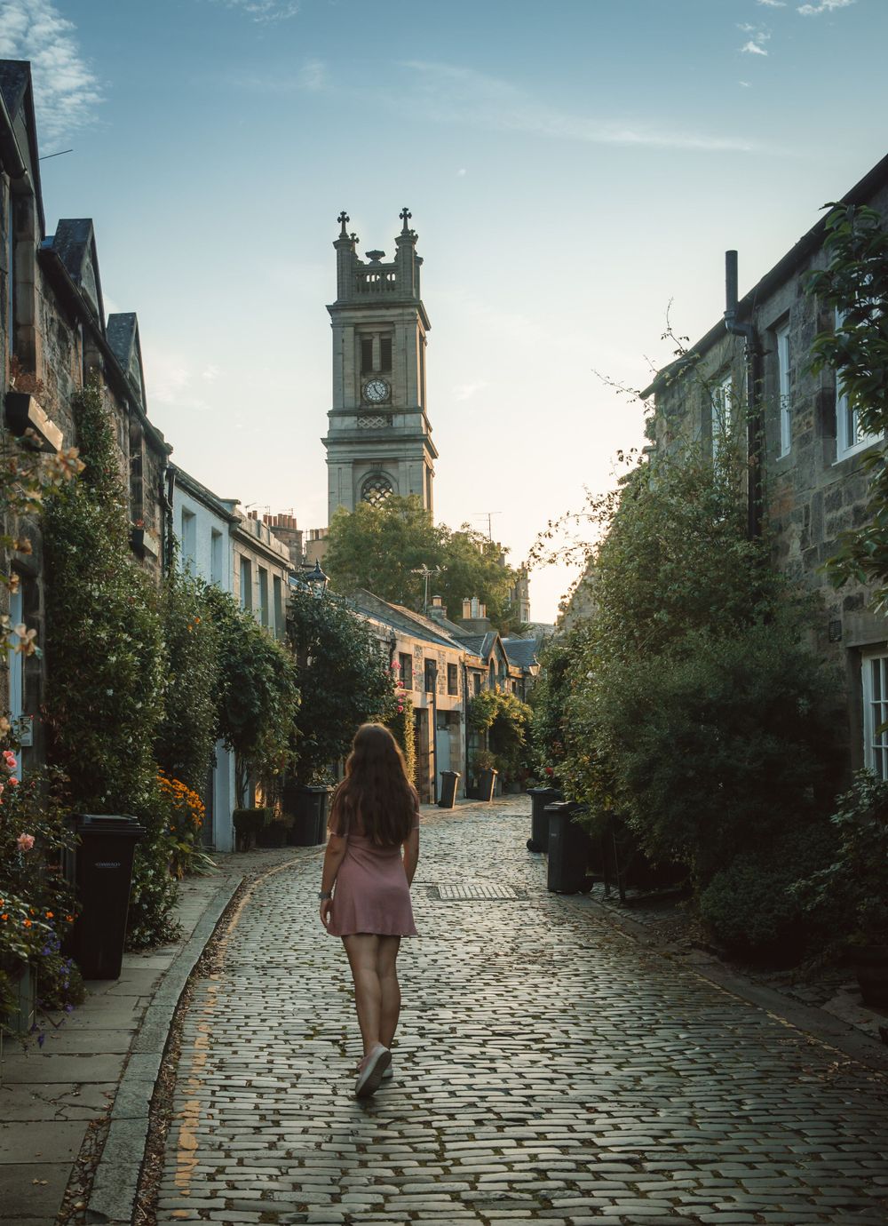 Cobblestone street leading to a church spire in a quaint European village.