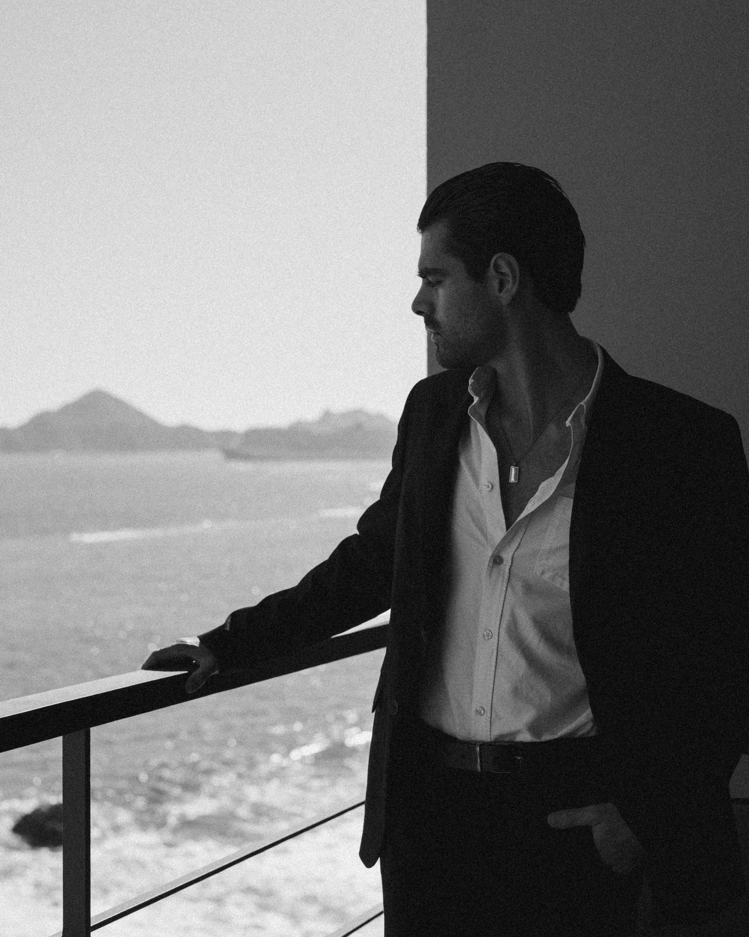 Silhouette of figures leaning against a railing overlooking an ocean view.