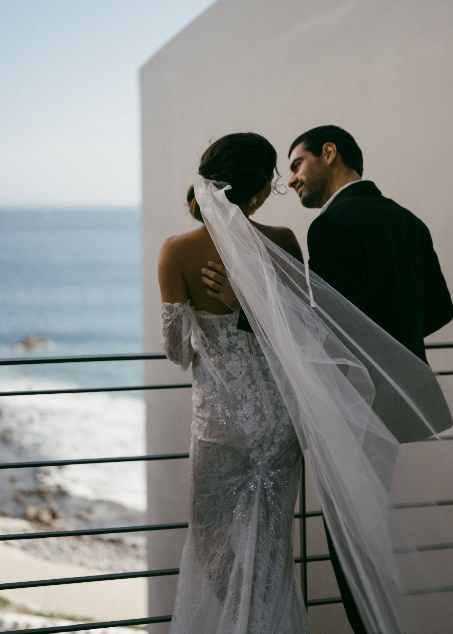 Wedding couple sharing an intimate moment on a seaside balcony.