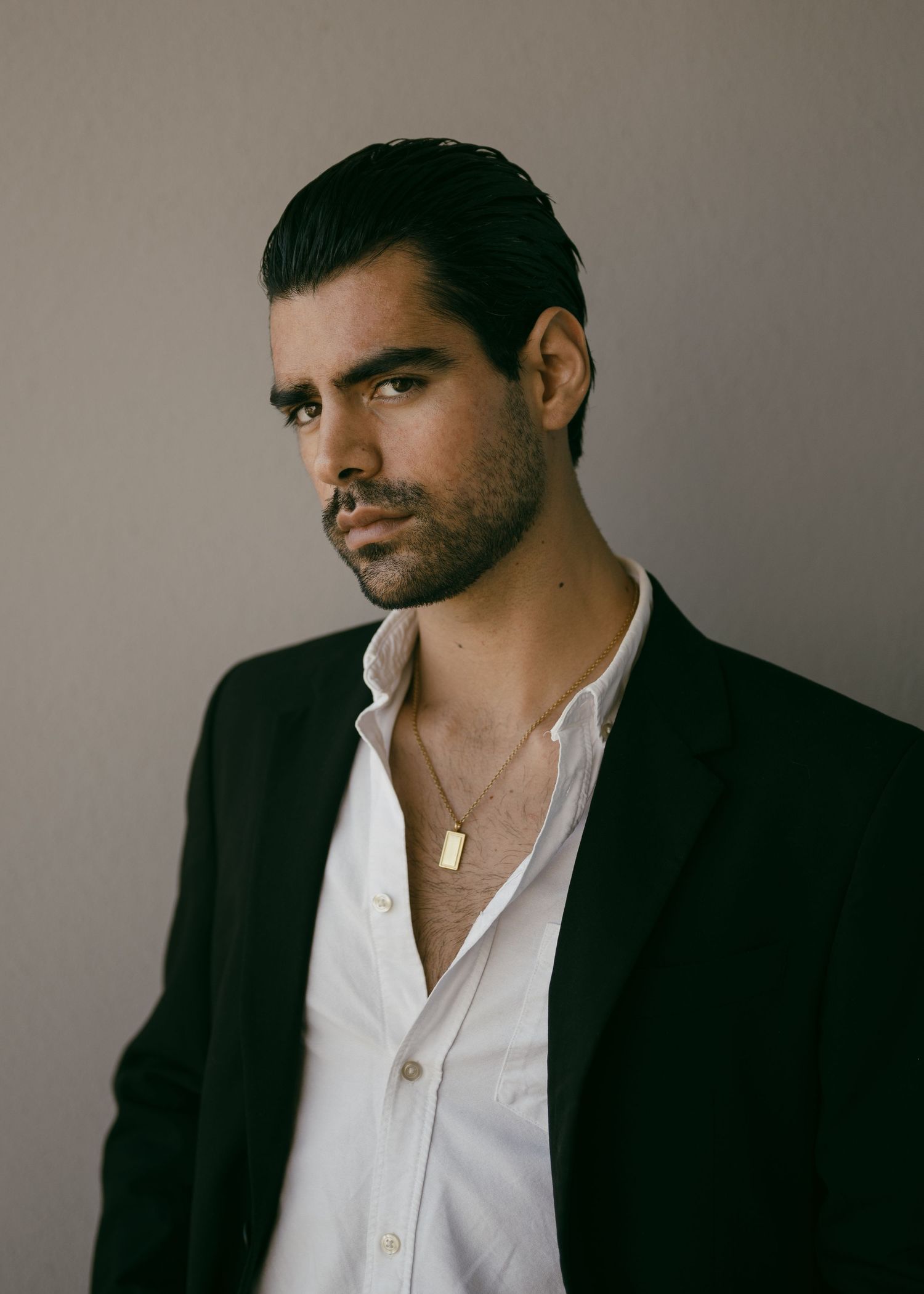 Artistic portrait in formal attire against a neutral background.