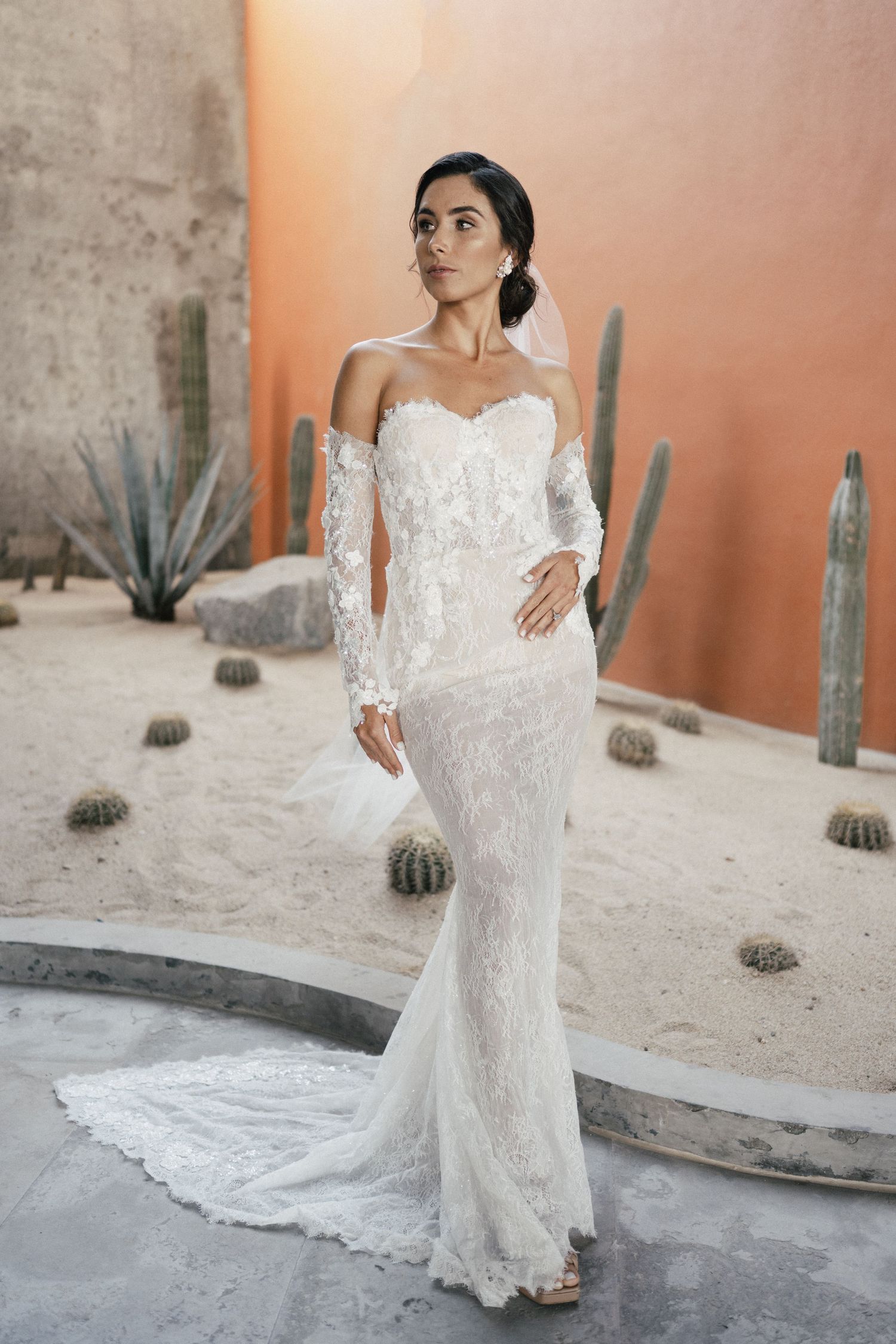 Elegant off-shoulder lace wedding dress with sweetheart neckline photographed against desert landscape with cacti.