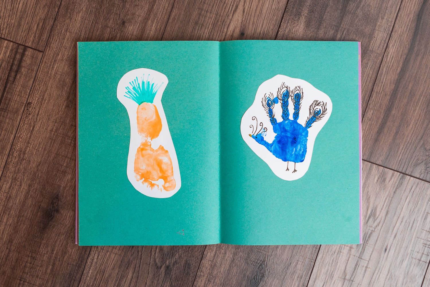 Handprint art created with orange and blue paint on green paper background.