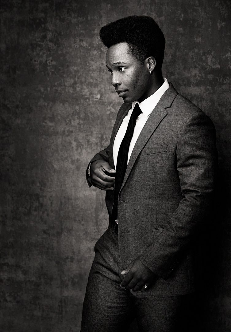 Professional studio portrait of a person in a suit against a dark textured background.
