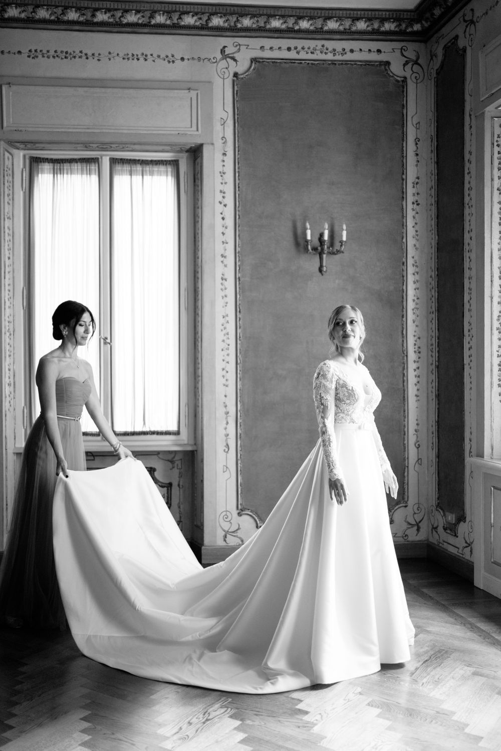 Dramatic black and white portraits showcasing a flowing wedding gown train in a historic room.