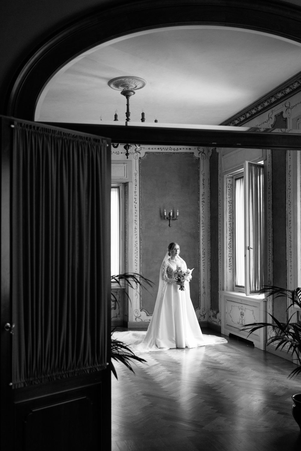 Dramatic black and white photos of wedding dress silhouette in a room with large windows and curtains.