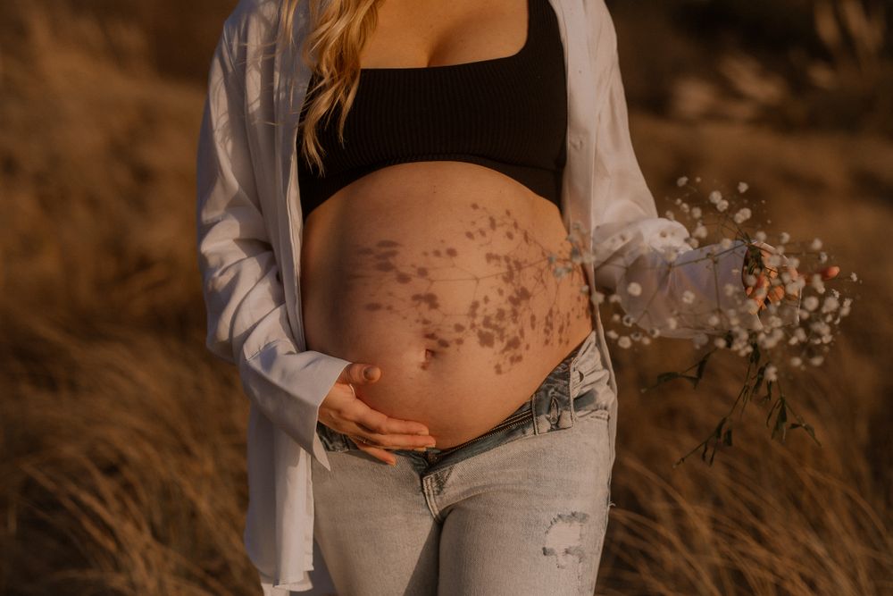 flowers and a pregnancy bump on raglan beach for maternity shoot