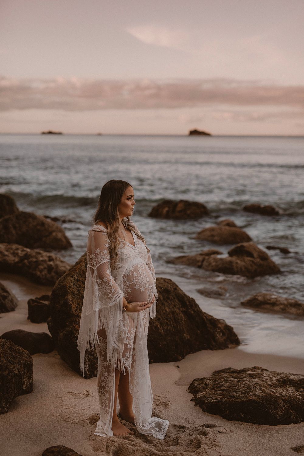 pink tones of sunset at the beach in bay of plenty for her maternity shoot