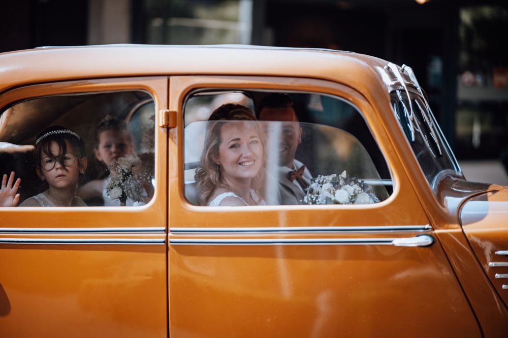 Vintage oranje auto met passagiers die door de ramen kijken.