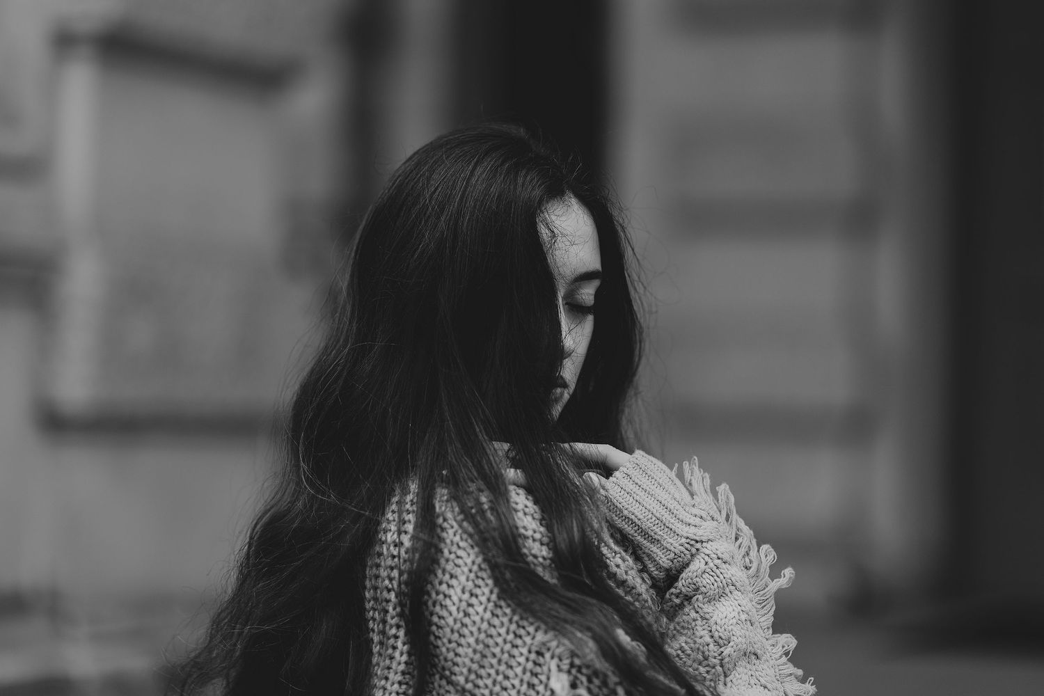 Artistic black and white portrait showing long dark hair and a textured sweater.