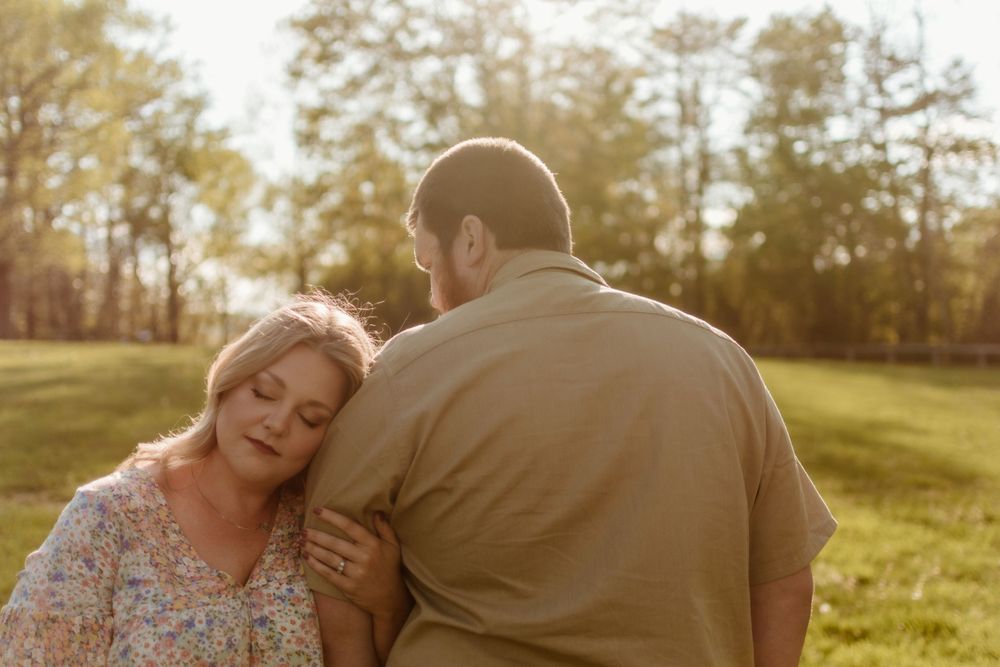 Romantic couple embracing in a sunlit field during golden hour.