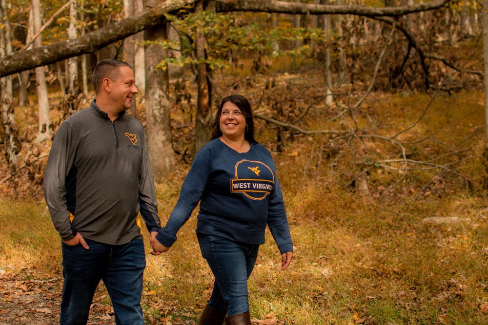 A couple takes a romantic walk through a forest trail during autumn.