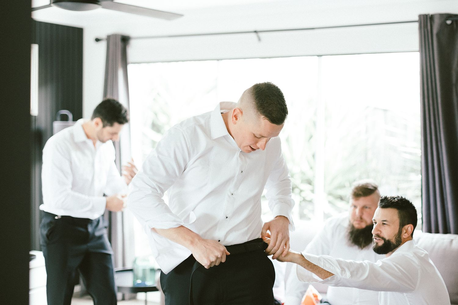 Men in white shirts getting ready in bright modern room.