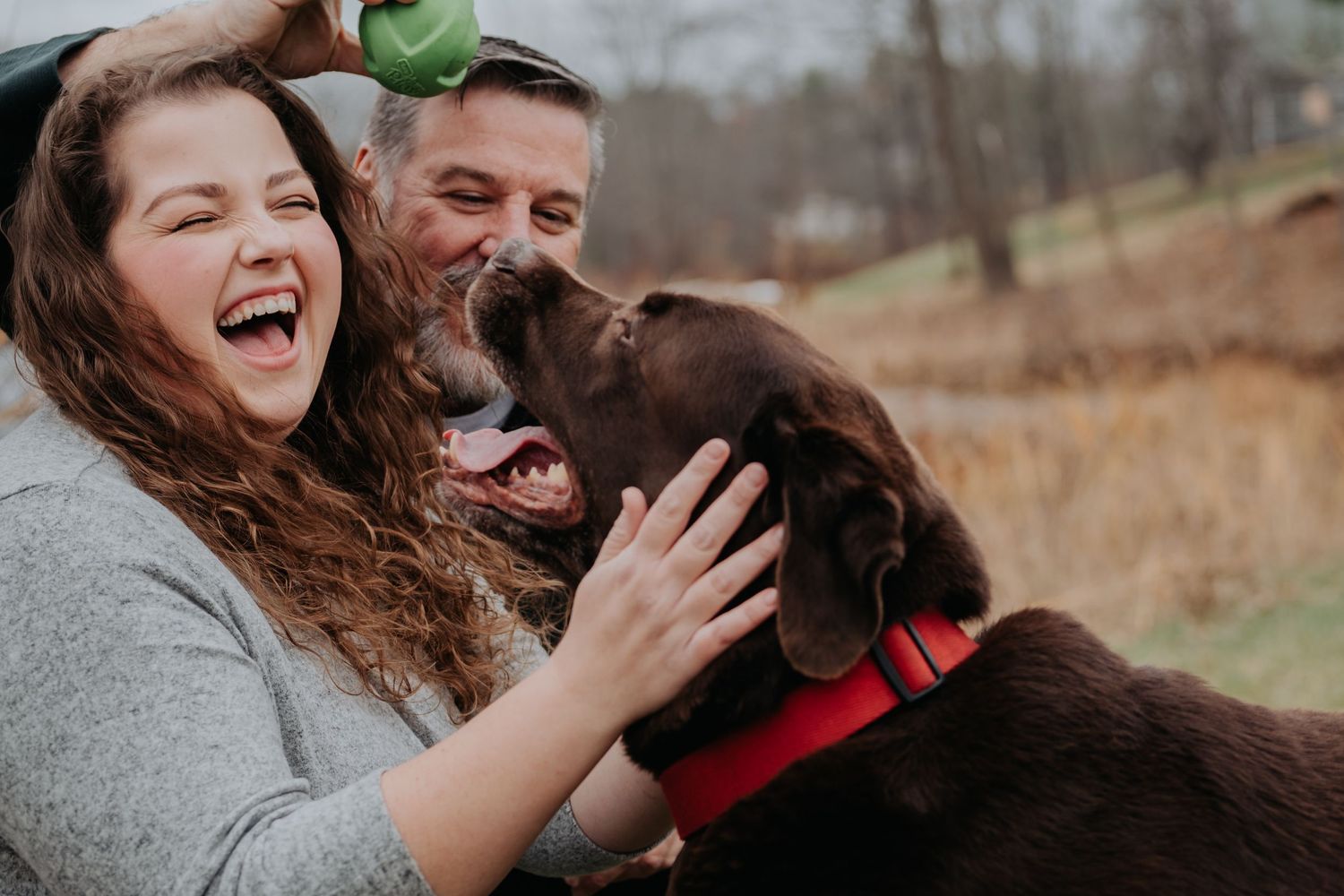a couple with their dog laughing and playing