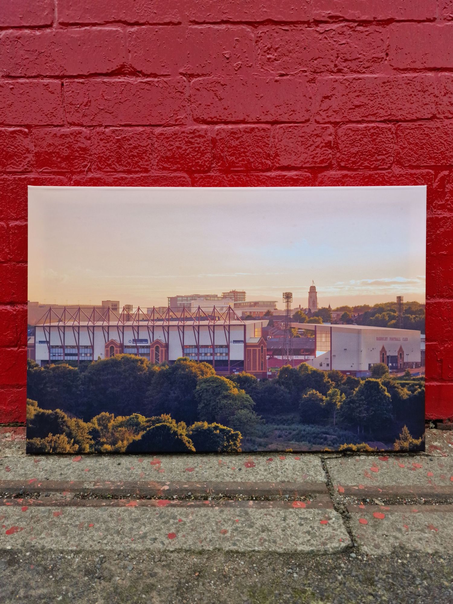 Urban skyline mural painted on a red brick wall showing industrial buildings at sunset.