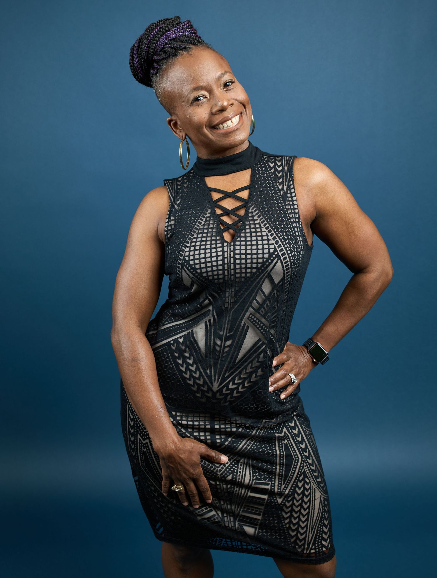 Fashion portraits in black studded top against deep blue studio backdrop.