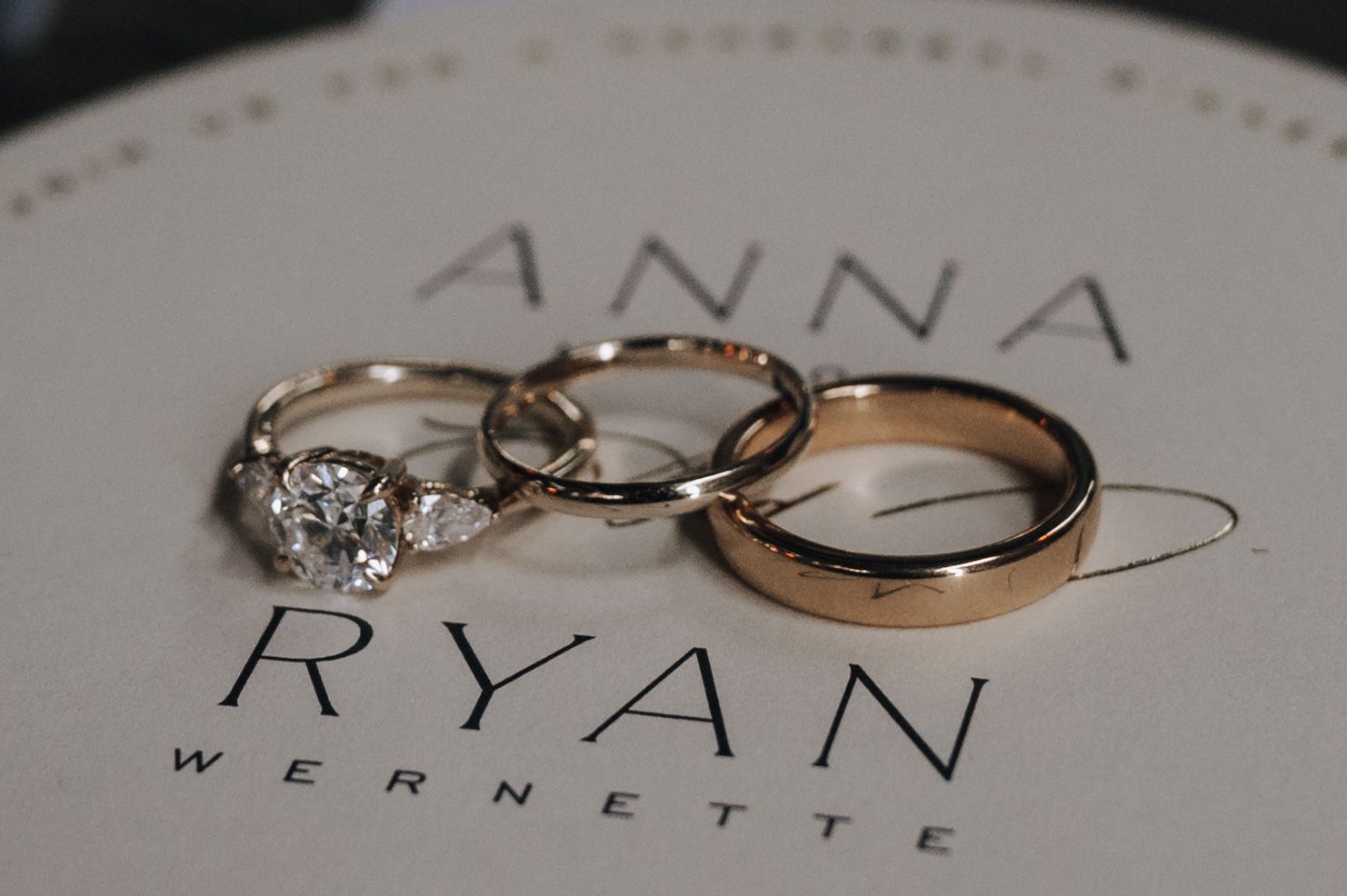 Wedding rings photographed on a white surface with names Anna and Ryan.