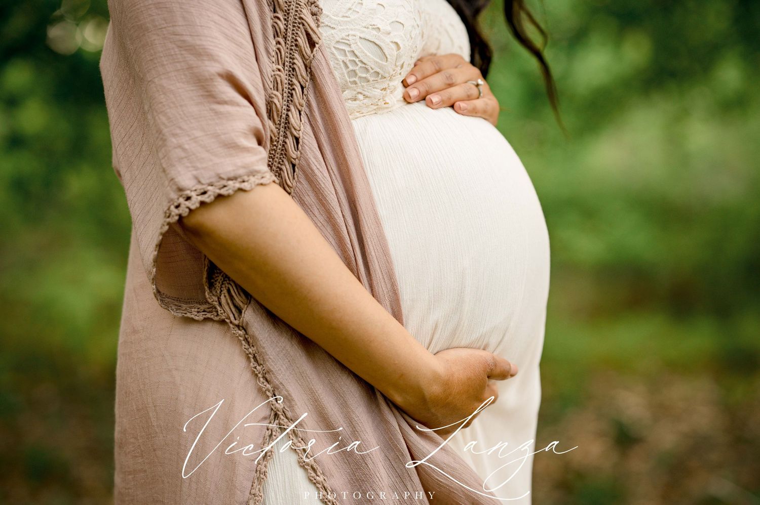 eight month pregnant belly portrait of mother holding belly while wearing white lace dress and mauve jacket
