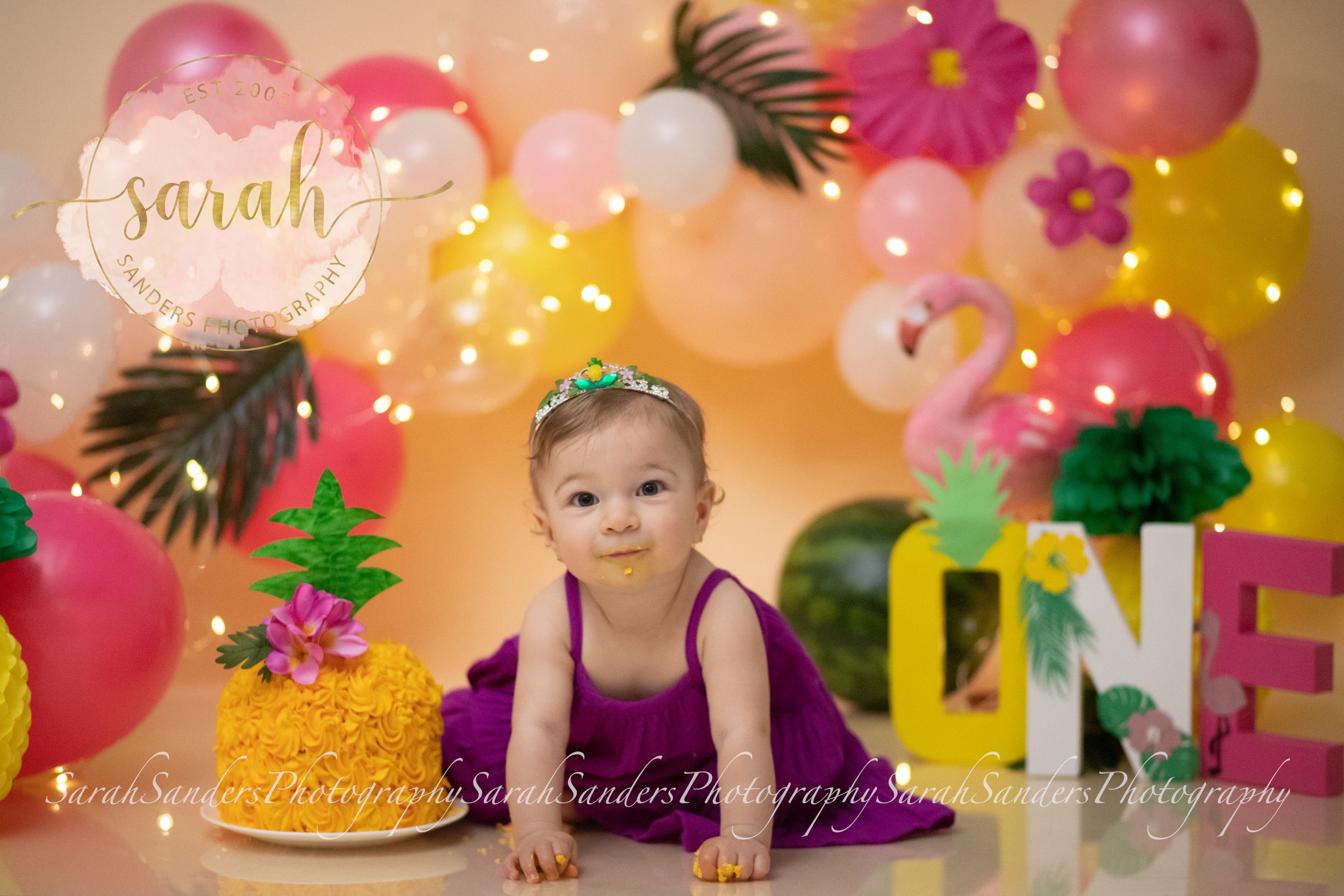 Baby sitting with cake in a summertime themed set