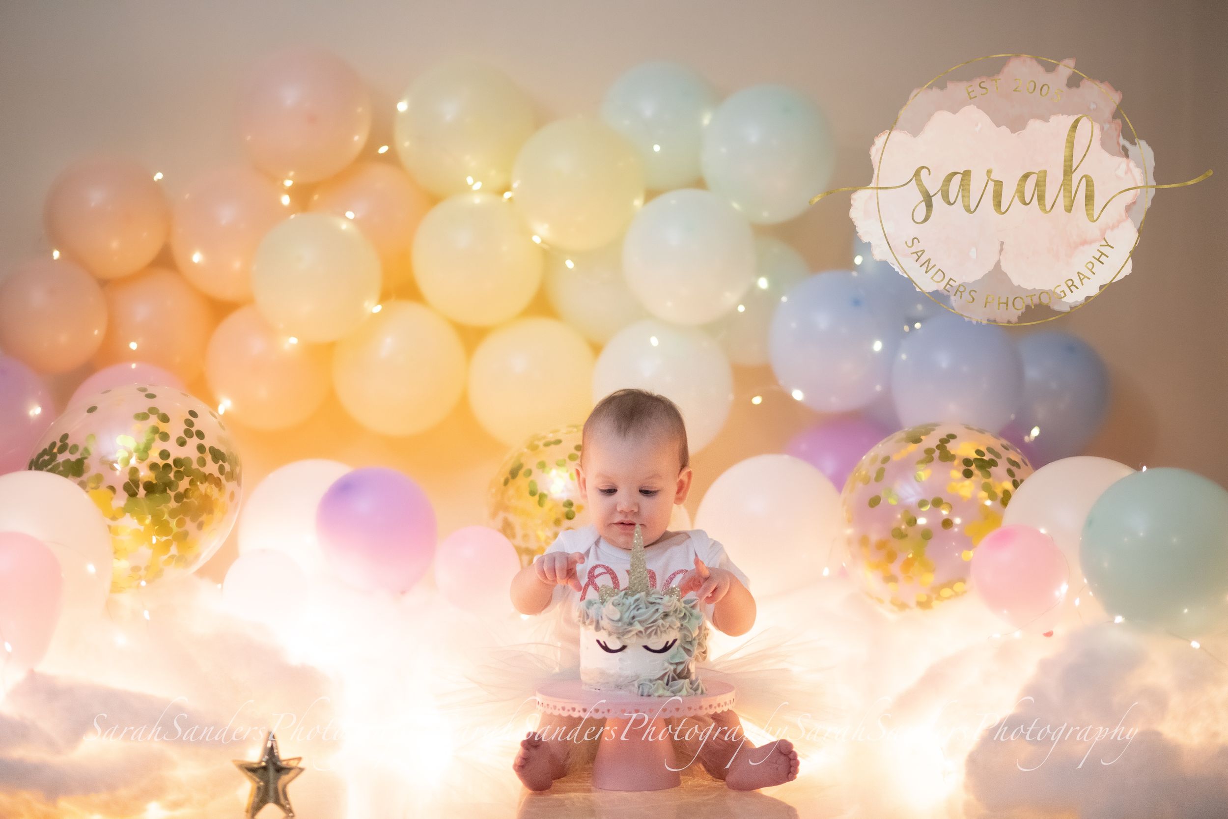 Baby sitting with cake in a rainbow with clouds themed set