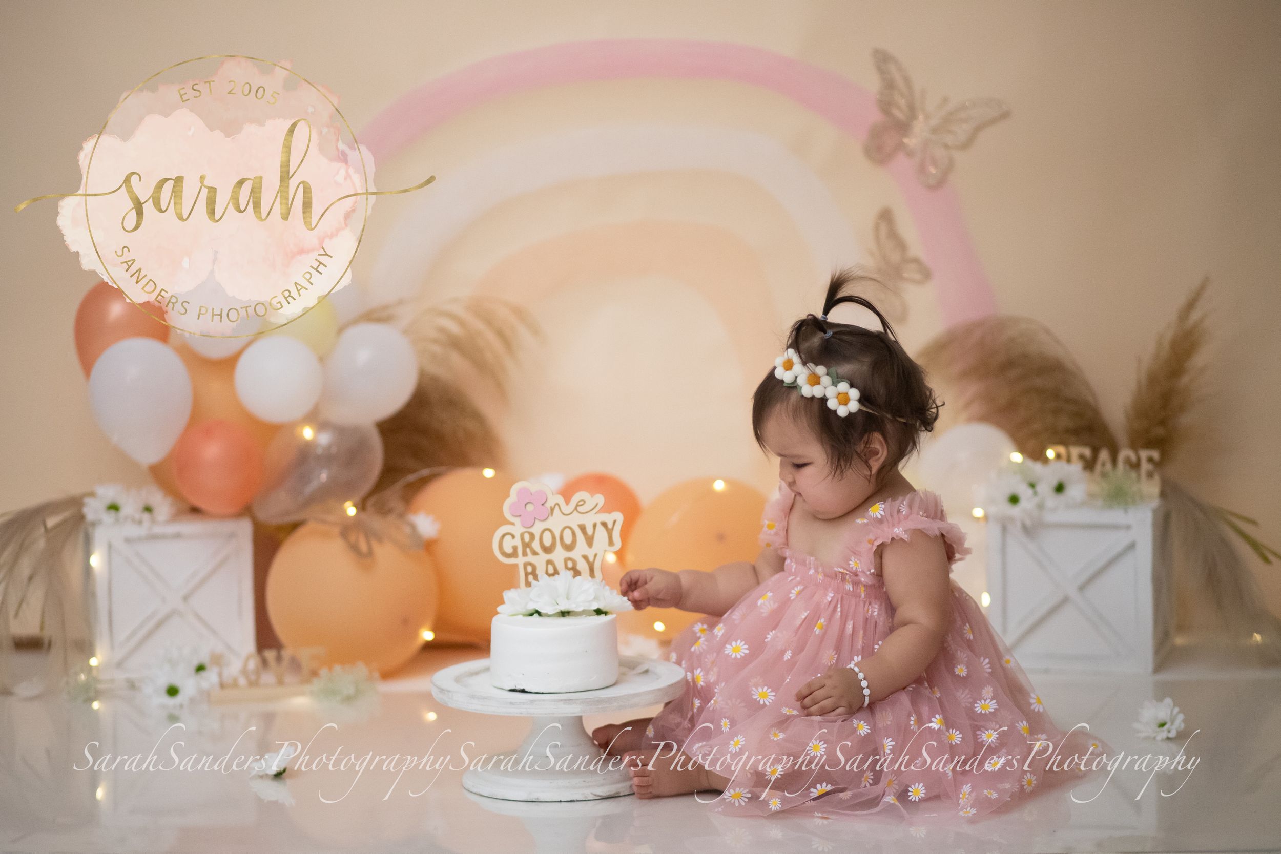Baby sitting with cake in a boho themed set