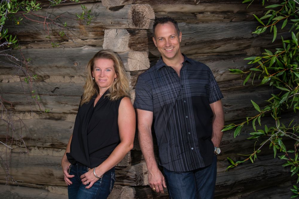 business lifestyle portrait:  Portrait of a woman and a man leaning on a log cabin