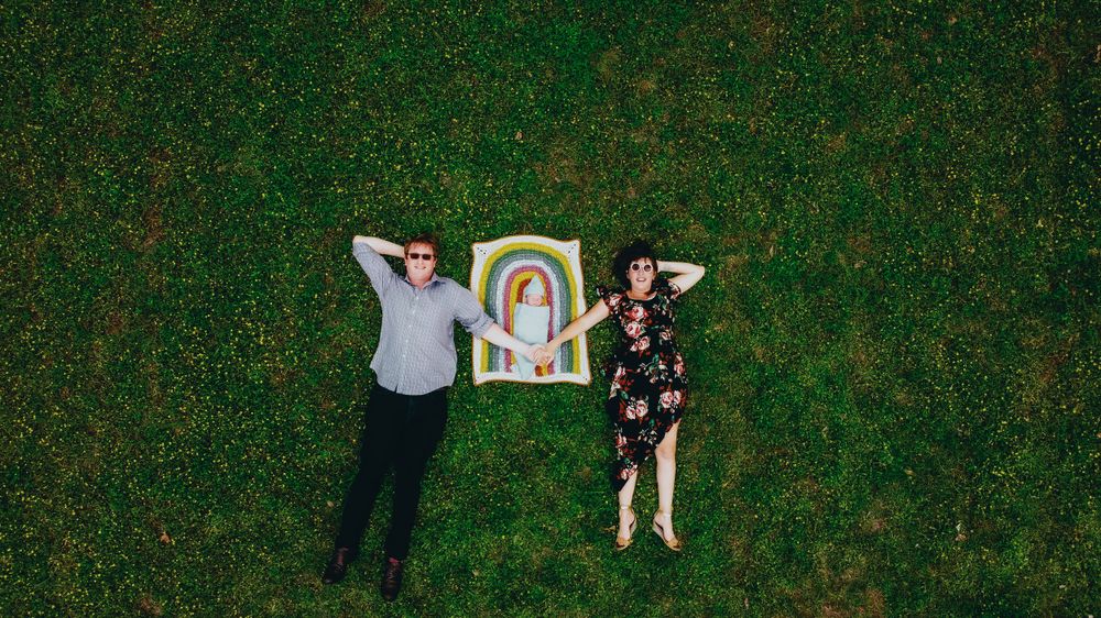 Aerial view of two people lying on grass next to a rainbow painting.