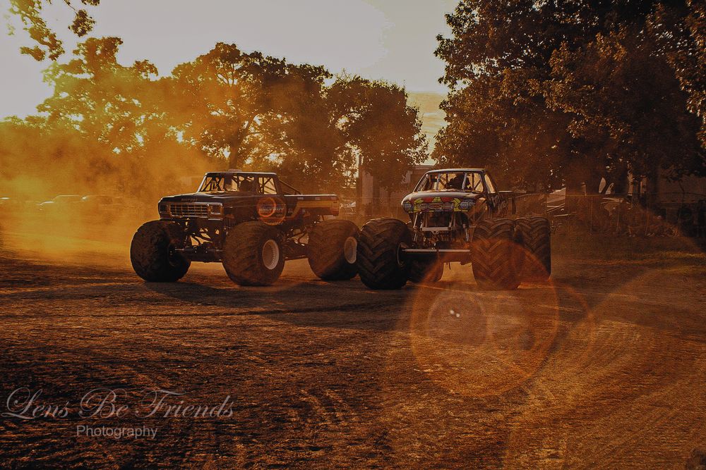 Off-road vehicles kicking up dust during sunset at an outdoor event.