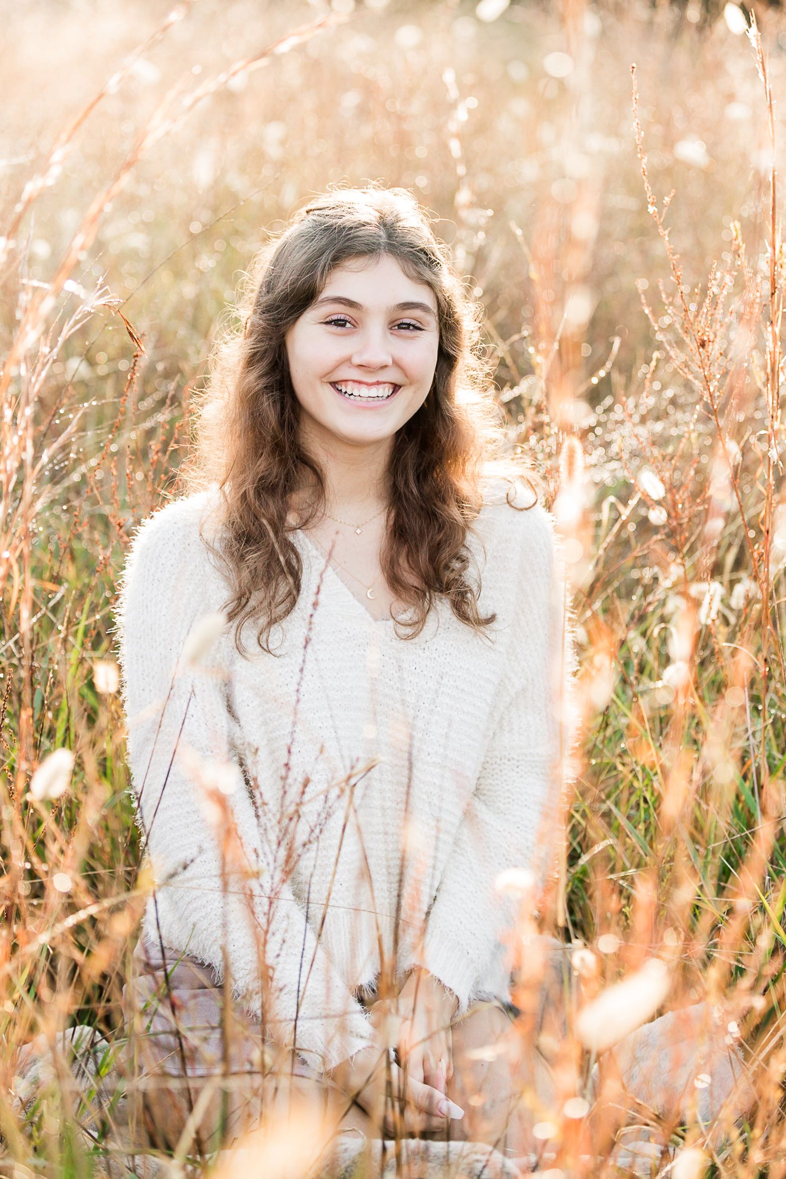 Senior girl posing in field of tall grass in fall
